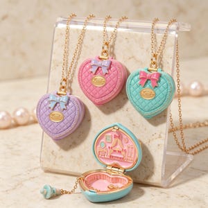 May include: Three heart-shaped lockets in lavender, pink, and teal, each with a gold chain and a small bow detail. One teal locket is open, revealing a miniature bedroom scene inside with a bed, vanity, and wardrobe, plus a tiny dangling charm.
