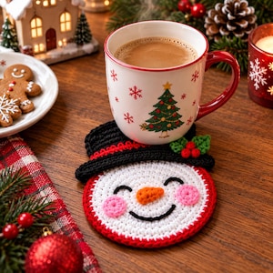 Könnte beinhalten: Ein runder, weiß gehäkelter Untersetzer mit einem lächelnden Schneemann-Gesicht, einer leuchtend orangefarbenen Karottennase, rosa Wangen und einem schwarzen Zylinder, der mit grünen Stechpalmenblättern und roten Beeren verziert ist.
