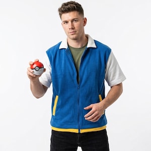 Könnte beinhalten: Eine blaue Reißverschlussweste mit weißem Kragen und weißen kurzen Ärmeln, getragen über einem olivgrünen T-Shirt. Die Weste hat gelbe Taschenakzente am unteren Rand. Ein kleiner, kugelförmiger Spielzeugball in Rot, Weiß und Grau wird gehalten.