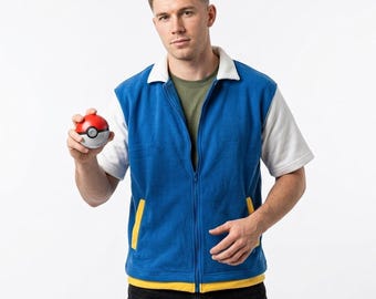 Puede incluir: Un chaleco azul con cremallera, cuello blanco y mangas cortas blancas, sobre una camiseta verde oliva. El chaleco tiene detalles de bolsillos amarillos en la parte inferior. Se sostiene una pequeña pelota de juguete roja, blanca y gris.