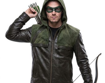 Puede incluir: Una chaqueta de cuero verde oscuro con capucha a juego y paneles de ante en los hombros, usada con un antifaz verde. El conjunto incluye un carcaj lleno de flechas en la espalda y un arco recurvo sostenido en la mano para un look completo.