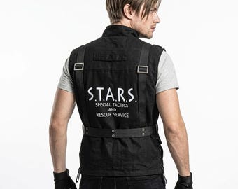 Puede incluir: Un chaleco táctico negro con texto blanco en la espalda que dice S.T.A.R.S. SPECIAL TACTICS AND RESCUE SERVICE. El chaleco incluye correas negras integradas con hebillas metálicas plateadas y un cinturón horizontal con ojales de metal.
