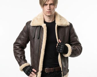 Puede incluir: Una chaqueta bomber de cuero marrón oscuro con un grueso forro de piel de oveja color crema, un cuello ancho doblado, cierre de cremallera frontal y dos correas con hebilla ajustables en el pecho. La chaqueta tiene mangas largas con puños de piel.