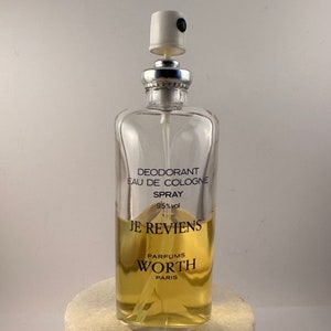 Può includere: Un flacone di vetro trasparente con un vaporizzatore argentato e un liquido giallo all'interno. Il flacone è etichettato "Deodorant Eau de Cologne Spray 95% vol Je Reviens Parfums Worth Paris".