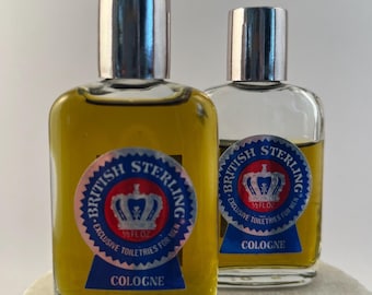 May include: Two clear glass bottles of British Sterling cologne with silver caps. Each bottle features a circular blue and red label with a crown graphic and the text British Sterling Exclusive Toiletries For Men 1/2 FL OZ.