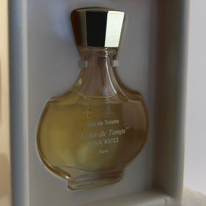 Op de afbeelding: Een doorzichtige glazen fles Nina Ricci L'Air du Temps Eau de Toilette parfum. De fles heeft een gouden dop en zit in een witte doos.