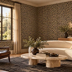 May include: A living room featuring a curved cream-colored sofa, a brown leather armchair, and an oval stone coffee table. The walls are covered in a tan wallpaper with a black spotted pattern, and a dark area rug sits on the wooden floor.