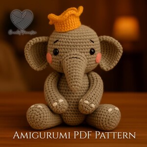 May include: A gray crocheted elephant amigurumi toy featuring a bright orange crown on its head, pink circular cheeks, black eyes, and white stitched details on its feet. The text Crochet Paradise and AMIGURUMI PDF PATTERN are visible.