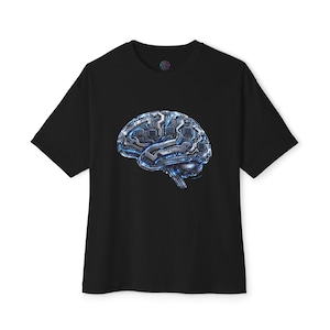 Puede incluir: Una camiseta negra de manga corta con un gráfico central de un cerebro humano construido con placas de circuito metálicas y vías electrónicas azules brillantes. El diseño muestra intrincados componentes de hardware plateados.