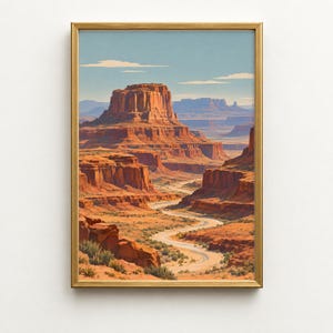 May include: A framed wall art print depicting a desert landscape with towering red rock mesas and buttes under a clear blue sky. A winding dirt road snakes through the canyon floor, surrounded by sparse desert vegetation and rocky terrain.