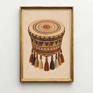 May include: A framed wall art print featuring a cylindrical drum with a tan top surface decorated with concentric circles and triangles. The drum body displays a geometric pattern of triangles and dots in rust, navy, and cream, finished with hanging tassels.