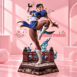Puede incluir: Una figura coleccionable detallada de un personaje con un vestido azul estilo qipao con adornos dorados, botas blancas y muñequeras con pinchos. La figura está posada dinámicamente sobre una base de piedra con una barandilla roja y efectos de agua.