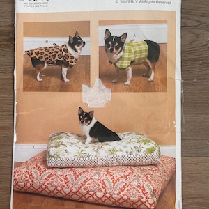 May include: Butterick B6303 WAVERLY sewing pattern envelope featuring illustrations of small dogs wearing a leopard print coat and a green plaid coat, plus a dog sitting on two stacked rectangular pet beds with floral and paisley patterns.