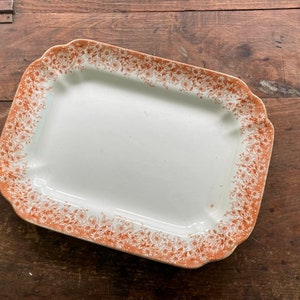 May include: A white ceramic serving platter with a scalloped edge and a floral pattern in shades of orange and brown.