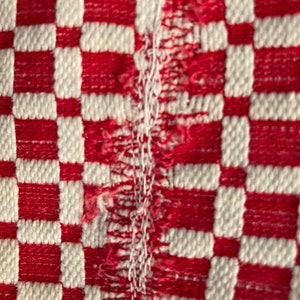 May include: Red and white checkered fabric with a frayed edge.