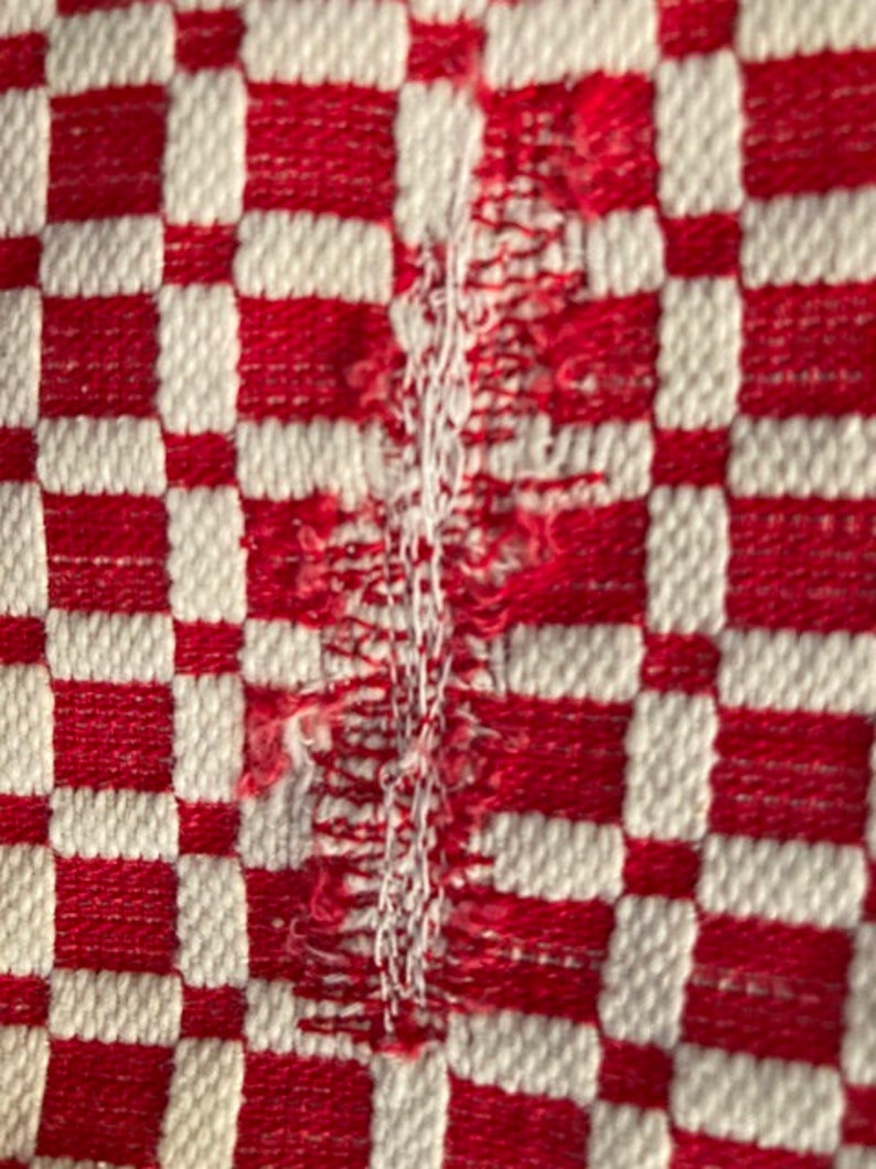 May include: Red and white checkered fabric with a frayed edge.