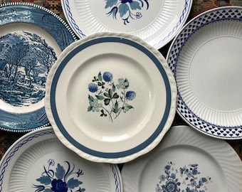 May include: Five white ceramic plates with blue floral designs. The plates have different patterns and styles, including a floral design with a blue rose, a floral design with blue clover, and a floral design with blue flowers.