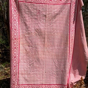 May include: A red and white checkered tablecloth with a Greek key border. The tablecloth is made of a woven fabric and has a vintage look.