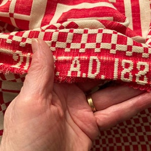 May include: Close-up of a red and white checkered fabric with a red woven label that reads "A.D. 1881".