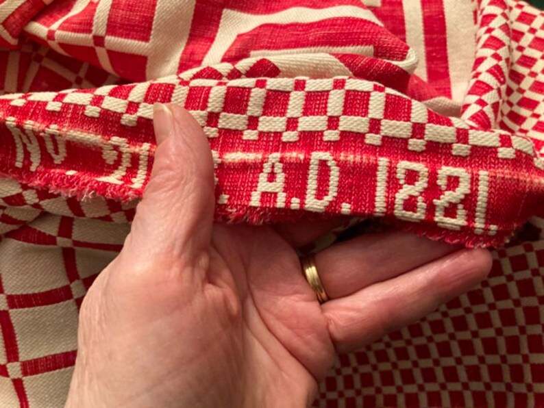 May include: Close-up of a red and white checkered fabric with a red woven label that reads "A.D. 1881".