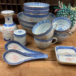 May include: A set of blue and white porcelain bowls, cups, and serving dishes with a floral pattern. The set includes a teapot, a small jar, and two serving spoons.