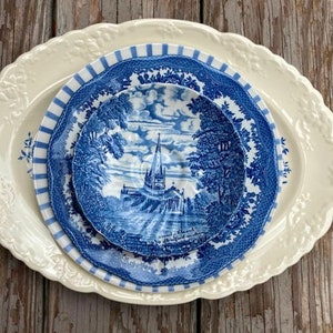 May include: Three blue and white porcelain plates with a vintage floral design. The smallest plate features a church in the center.