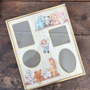 May include: A gold-framed picture frame with spaces for multiple photos. The frame is decorated with cartoon animals, including a panda, teddy bear, and bunny. The background has a dotted pattern.