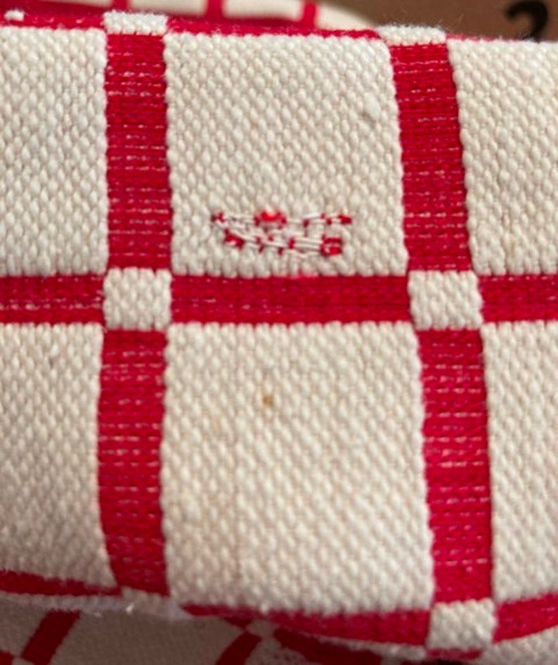 May include: Close-up of a white and red checkered fabric with a small red thread detail in the center.