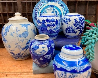 May include: A collection of blue and white porcelain jars and a plate with a floral design. The jars have lids and are decorated with various patterns, including flowers, birds, and geometric shapes.