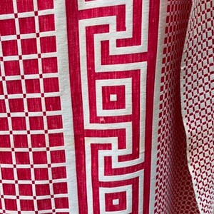 May include: Red and white fabric with a geometric pattern. The fabric has a white border with a repeating Greek key design.