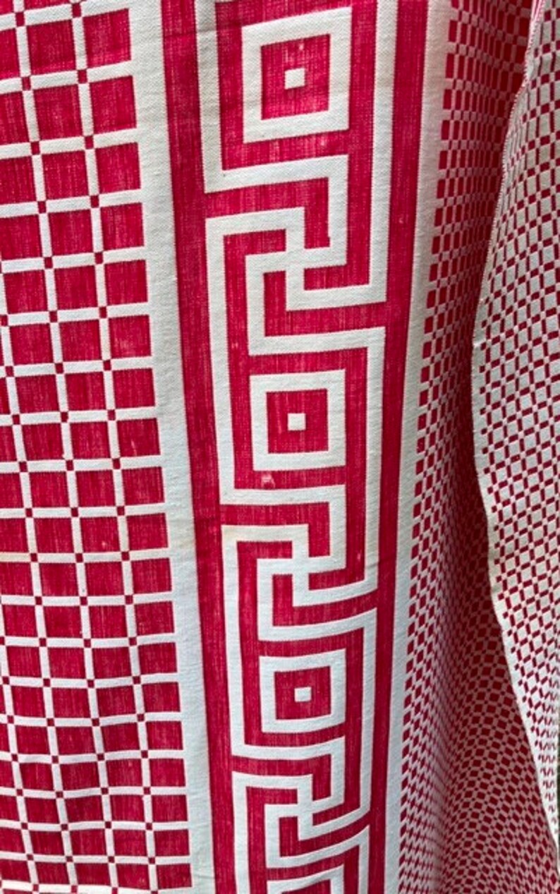 May include: Red and white fabric with a geometric pattern. The fabric has a white border with a repeating Greek key design.