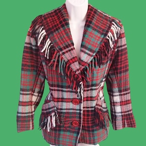 May include: A vintage plaid jacket in red, black, green, and white. The jacket features a fringed collar and pockets, with red buttons. The jacket is displayed on a white mannequin.