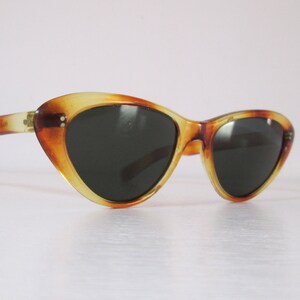 Puede incluir: Gafas de sol de ojo de gato con un patr&oacute;n de carey. Las monturas presentan tonos &aacute;mbar y marr&oacute;n, con lentes oscuras. Estas gafas tienen una est&eacute;tica retro y vintage.