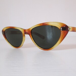 Puede incluir: Gafas de sol vintage de ojo de gato con un patr&oacute;n de carey. Las monturas son una mezcla de &aacute;mbar y marr&oacute;n, con lentes oscuras. Estas gafas de sol tienen un dise&ntilde;o cl&aacute;sico y retro, perfectas para un toque vintage.