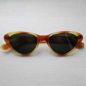 Puede incluir: Gafas de sol de ojo de gato con un patr&oacute;n de carey. Las monturas son &aacute;mbar y marr&oacute;n, con lentes oscuras. Las gafas de sol tienen un dise&ntilde;o retro cl&aacute;sico.