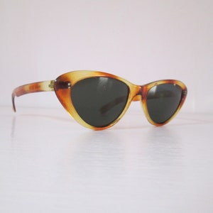 Puede incluir: Gafas de sol vintage de ojo de gato con estampado de carey. Las monturas son una mezcla de tonos &aacute;mbar y marr&oacute;n, con lentes oscuras. Dise&ntilde;o retro cl&aacute;sico.