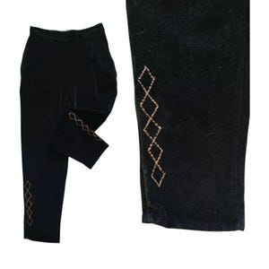 Puede incluir: Pantalones de terciopelo negro con corte recto. Los pantalones presentan un patrón de diamantes decorativo en color dorado a lo largo de la costura exterior de la pierna. Un estilo clásico.