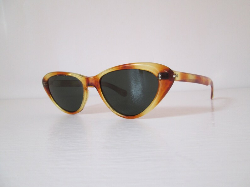 Puede incluir: Gafas de sol vintage de ojo de gato con un patr&oacute;n de carey. Las monturas son una mezcla de &aacute;mbar y marr&oacute;n, con lentes oscuras. Estas gafas de sol tienen un dise&ntilde;o cl&aacute;sico y retro, perfectas para un toque vintage.