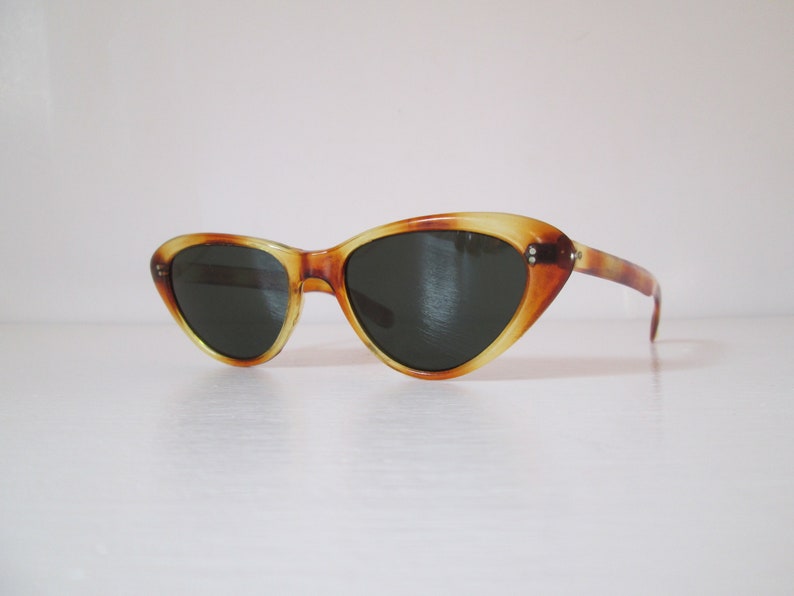 Puede incluir: Gafas de sol vintage de ojo de gato con un patr&oacute;n de carey. Las monturas son &aacute;mbar y marr&oacute;n, con lentes oscuras. Las gafas de sol tienen un dise&ntilde;o cl&aacute;sico y retro.