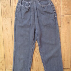 May include: A pair of gray denim pants with a high waist and straight leg. The pants have front pockets with white stitching and a button closure. The fabric appears to be a medium weight denim.