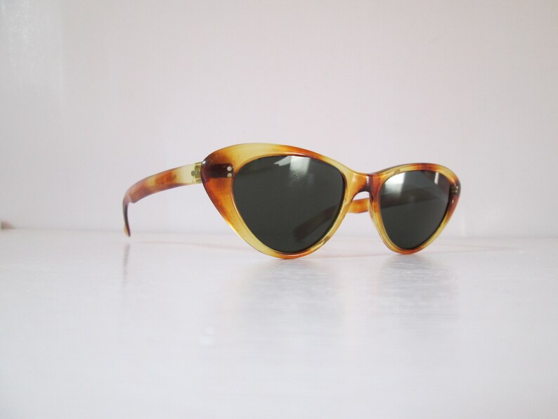 Puede incluir: Gafas de sol vintage de ojo de gato con estampado de carey. Las monturas son una mezcla de &aacute;mbar y marr&oacute;n, con lentes oscuras. Dise&ntilde;o retro cl&aacute;sico.