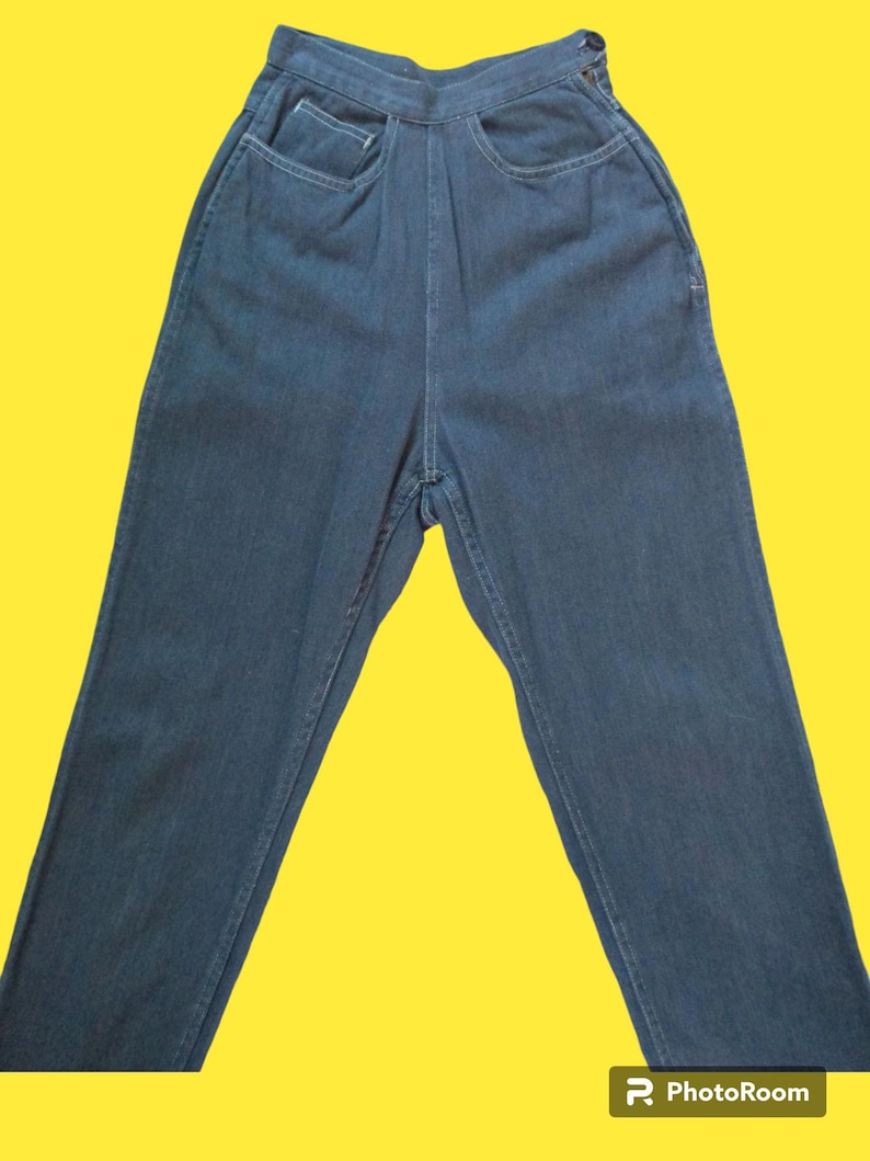 May include: Dark blue denim jeans with a high waist and two front pockets. The jeans have a classic five-pocket design and a button closure. The denim appears to be a medium weight, suitable for everyday wear.