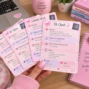 May include: A set of pink and white study cards for radiologic technology, featuring headers like PA Chest, Lateral Wrist, and AP Elbow. Each card includes technical positioning details, degree of angulation, central ray points, KVP, and mAs values.