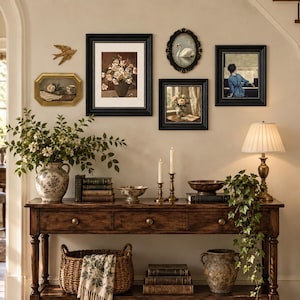 May include: A dark wood console table with three drawers and a lower shelf, featuring a ceramic vase with greenery, a woven basket with a patterned cloth, stacked books, two brass candlesticks, a bowl, a lamp, and a trailing ivy plant.