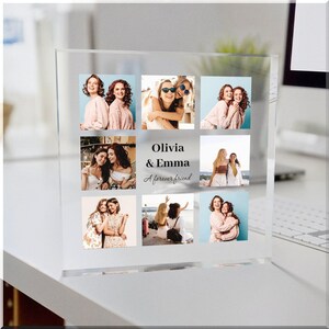 May include: A square clear acrylic photo block featuring a grid of eight photographs of two friends and a central text section that reads Olivia & Emma A forever friend. The transparent block displays various candid moments of the pair.