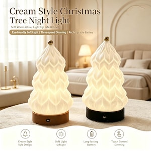 May include: Two Christmas tree-shaped night lights with white, textured, petal-like surfaces and gold-toned toppers. One lamp has a light wood-colored base, the other a black base. Text includes: Cream Style Christmas Tree Night Light.