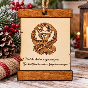 May include: A rectangular wooden hanging ornament featuring a laser-engraved nativity scene of a baby in a manger. The text reads, "And this shall be a sign unto you; Ye shall find the babe... lying in a manger." It has dark wood borders.