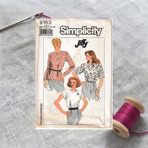 May include: A Simplicity Jiffy sewing pattern envelope, number 9163, size UU, featuring illustrations of three different tops worn with skirts. The white paper envelope displays the brand name, pattern number, and sketches of garments.