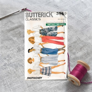 May include: A Butterick Classics 3960 sewing pattern envelope featuring illustrations of five different pant and skirt styles. The white paper envelope displays the text Butterick Classics 3960, Very Easy, and sizes 18-20-22, with a needle and purple thread.