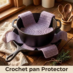 May include: A light purple crochet pan protector with a spiral center and four extended rectangular flaps, positioned inside a black cast iron pot which is resting on a black cast iron skillet, creating a layered kitchen storage setup.